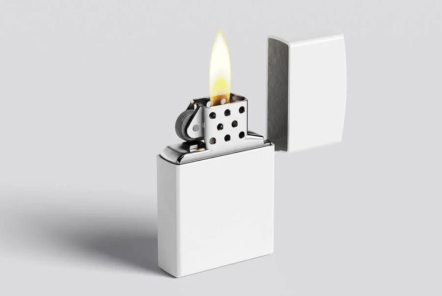 Open polished silver flip-top lighter with a blank front face, yellow flame, and lid behind it on a pale gray surface.